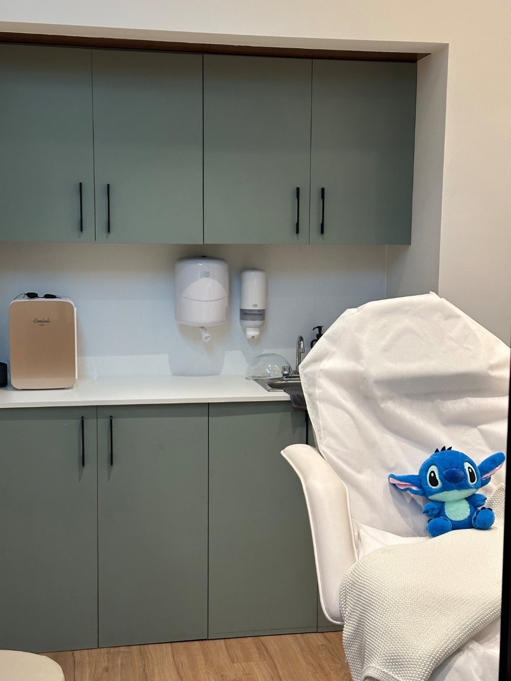 Sala de tratamiento del consultorio: gabinetes color salvia, área de trabajo y camilla